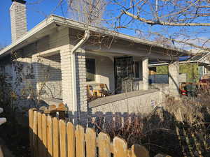 View of side of home with brick siding, a fenced front yard, and a chimney