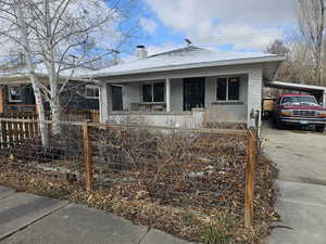 Bungalow featuring an attached carport, brick siding, driveway, and a chimney