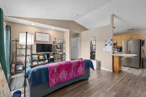 Living area with lofted ceiling, dark wood-style floors, visible vents, and baseboards