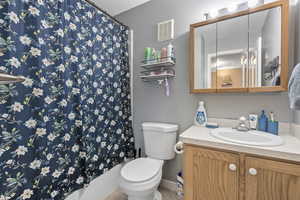 Full bathroom with toilet, a textured ceiling, vanity, and visible vents