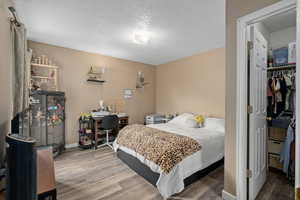 Bedroom featuring a textured ceiling, baseboards, and wood finished floors