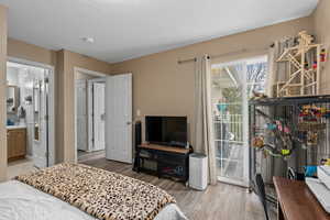 Bedroom featuring a textured ceiling, ensuite bath, and wood finished floors