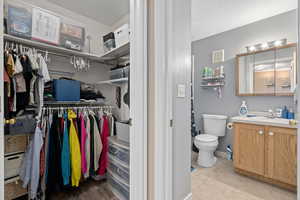 Bathroom featuring a walk in closet, visible vents, toilet, vanity, and tile patterned floors