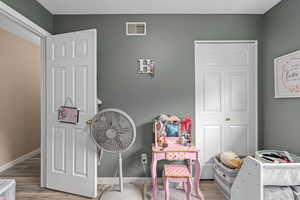 Bedroom with wood finished floors, visible vents, and baseboards