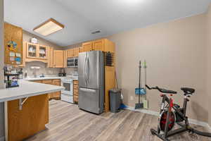 Kitchen with visible vents, glass insert cabinets, appliances with stainless steel finishes, light countertops, and a sink