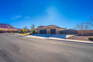 View of front of house featuring a garage, driveway, stone siding, fence, and a mountain view