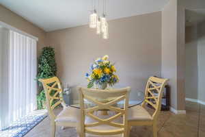 Dining area featuring light tile patterned floors, baseboards, and a notable chandelier