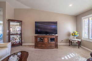 Living room featuring baseboards, lofted ceiling, and light colored carpet