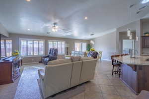 Living room featuring light tile patterned floors, baseboards, visible vents, a ceiling fan, and a textured ceiling