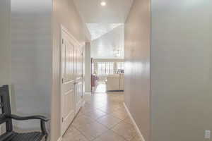 Corridor featuring light tile patterned floors, baseboards, and a textured ceiling