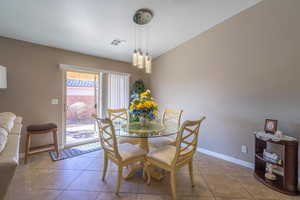 Dining area featuring light tile patterned flooring, visible vents, baseboards, and a textured ceiling