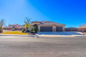 View of front of property with a garage, concrete driveway, stone siding, and stucco siding