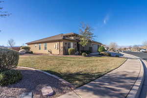 View of side of home with an attached garage, a yard, driveway, and stucco siding