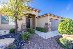 View of front of property with a garage, stone siding, and stucco siding