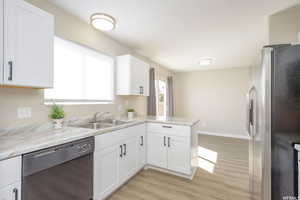 Kitchen with white cabinetry, a sink, dishwasher, a peninsula, and stainless steel fridge with ice dispenser