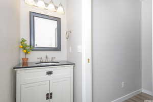 Bathroom with vanity, baseboards, and wood finished floors