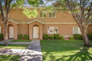 View of front of house featuring a tiled roof, a front lawn, and stucco siding