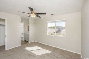 Unfurnished bedroom with light carpet, visible vents, baseboards, a closet, and ensuite bath