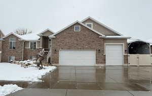 View of front of home with a garage, driveway, brick siding, and a gate