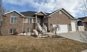 View of front of property with concrete driveway, brick siding, an attached garage, and a front yard