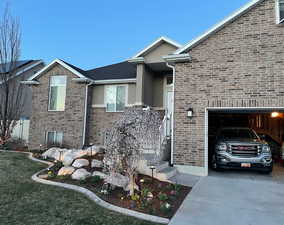 View of front of property featuring concrete driveway, brick siding, and an attached garage