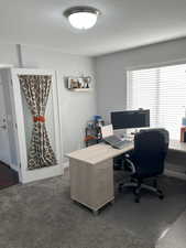 Office area with dark colored carpet and a textured ceiling