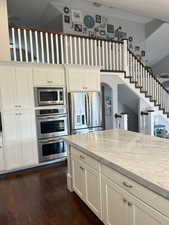 Kitchen featuring appliances with stainless steel finishes, white cabinets, and light stone counters