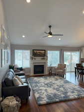 Living room with dark wood-type flooring, recessed lighting, a ceiling fan, and a premium fireplace