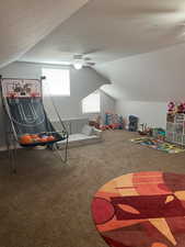 Game room featuring carpet floors, a ceiling fan, vaulted ceiling, and a textured ceiling