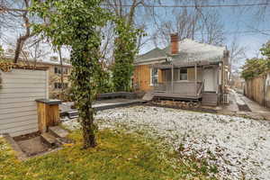 Back of property featuring a shingled roof, covered porch, fence, and a chimney