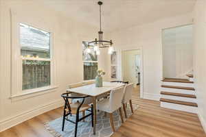 Dining room with light wood finished floors, stairs, baseboards, and a chandelier