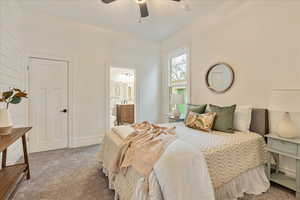 Carpeted bedroom featuring connected bathroom and ceiling fan