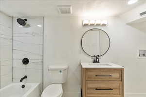 Bathroom featuring visible vents, toilet, vanity, shower / tub combination, and a textured ceiling