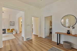 Corridor featuring light wood-style floors, visible vents, and baseboards