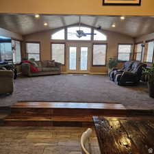 Carpeted living area with a ceiling fan, lofted ceiling, french doors, and a textured ceiling