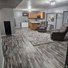 Living room with a textured ceiling, dark wood-style flooring, and baseboards