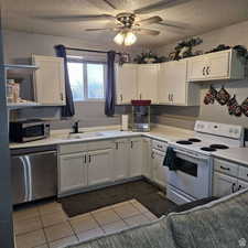 Kitchen with a textured ceiling, a sink, white cabinetry, light countertops, and appliances with stainless steel finishes