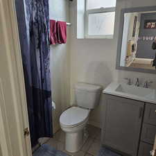 Full bath with a textured wall, toilet, vanity, tile patterned flooring, and baseboards