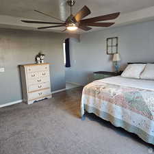 Bedroom with baseboards, dark carpet, ceiling fan, and a textured ceiling