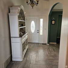 Foyer entrance with arched walkways, an inviting chandelier, visible vents, and baseboards