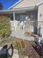 Entrance to property with a porch and brick siding