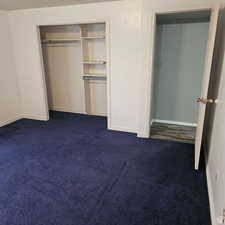 Unfurnished bedroom with dark colored carpet, a closet, and baseboards