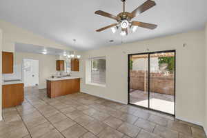 Kitchen with lofted ceiling, a peninsula, visible vents, light countertops, and brown cabinets