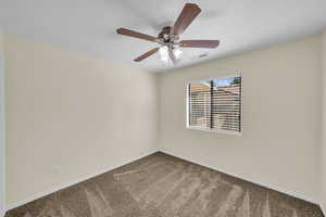 Carpeted empty room featuring a ceiling fan, visible vents, and baseboards