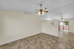 Spare room featuring lofted ceiling, baseboards, and ceiling fan with notable chandelier