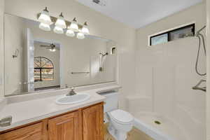 Full bathroom with toilet, visible vents, a stall shower, and vanity