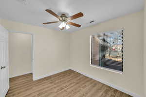 Spare room featuring a ceiling fan, visible vents, light wood-style flooring, and baseboards