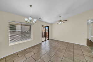 Unfurnished room featuring light tile patterned floors, visible vents, vaulted ceiling, and ceiling fan with notable chandelier