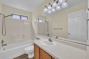 Bathroom with toilet, shower / bath combination, wood finished floors, and vanity