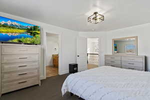 Bedroom featuring dark carpet, connected bathroom, and baseboards